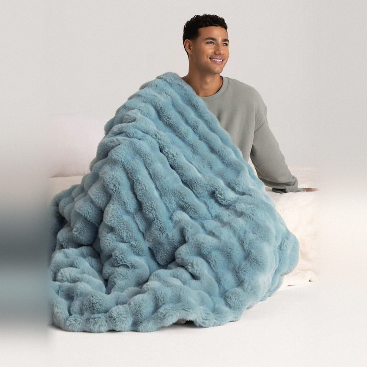Mochi Mellow Cloud Heated Lavender Throw in Blue — Blue heated lavender throw draped over a bed with a man sitting behind it