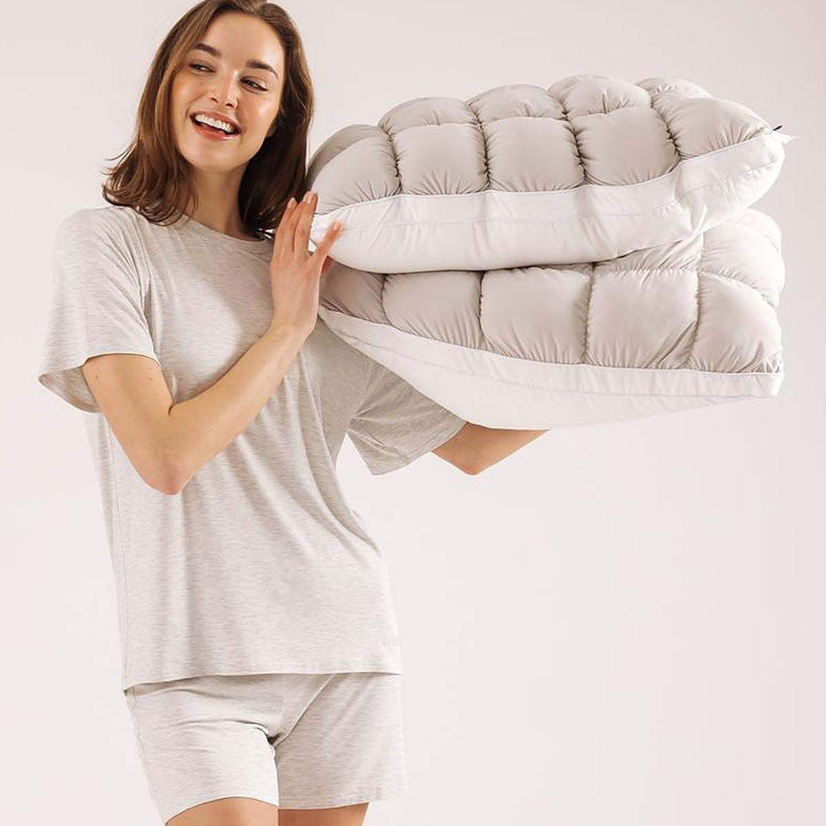 Woman carrying the folded Mochi Mellow Cloud comforter over one shoulder