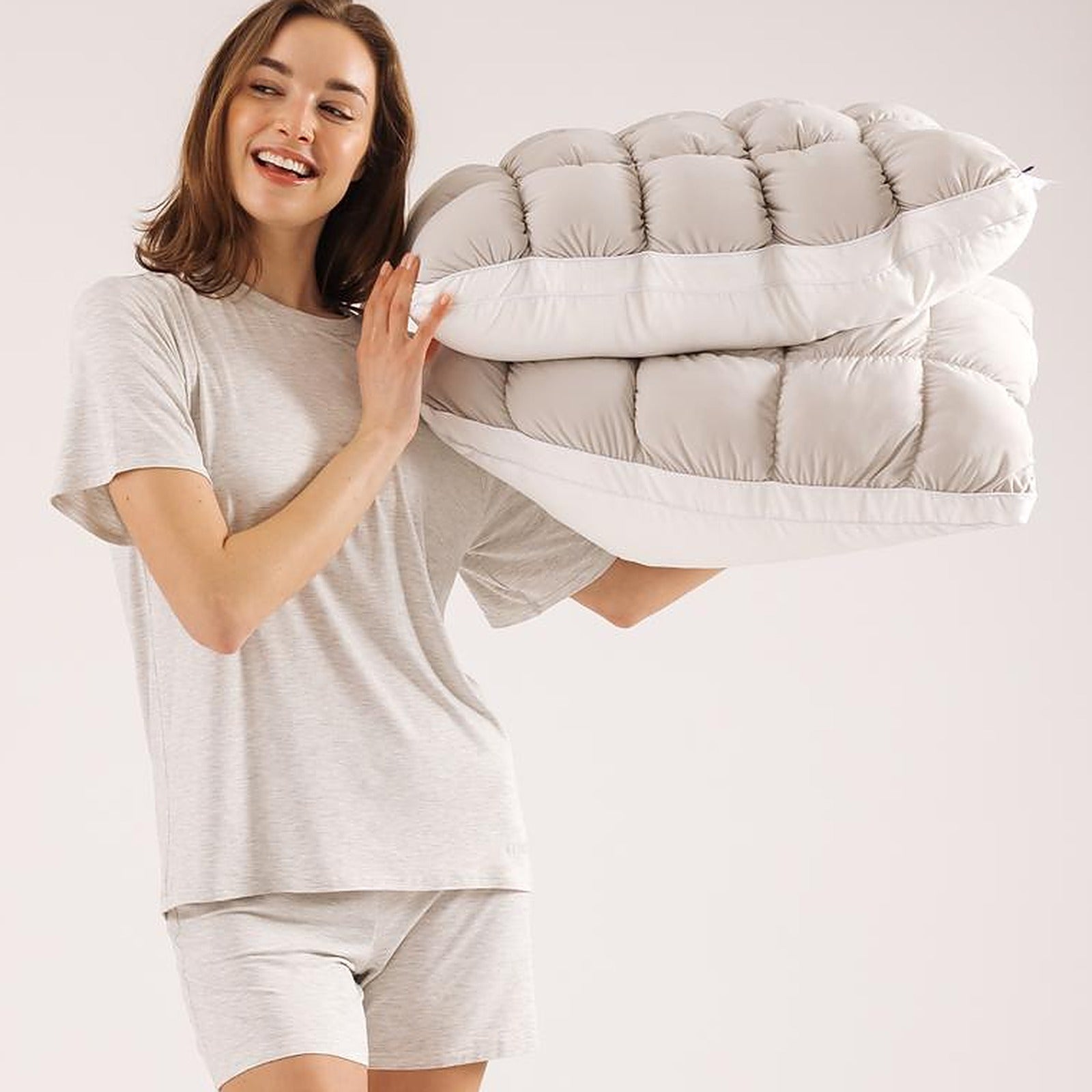 Woman carrying the folded Mochi Mellow Cloud comforter over one shoulder