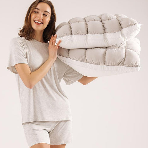 Woman carrying the folded Mochi Mellow Cloud comforter over one shoulder