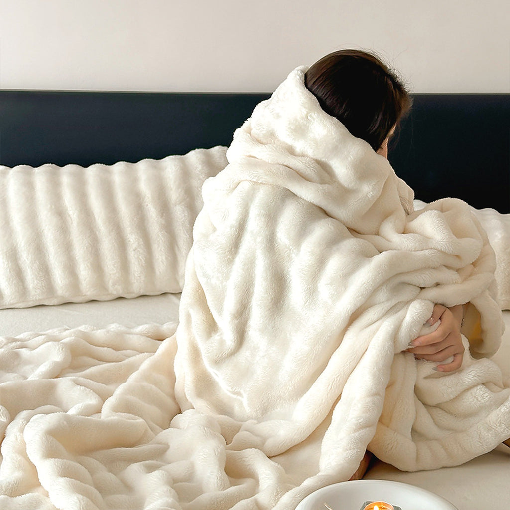 Mochi Mellow Cloud Throw in Frost — Frost white ruched faux-fur throw wrapped around a woman sitting on a bed