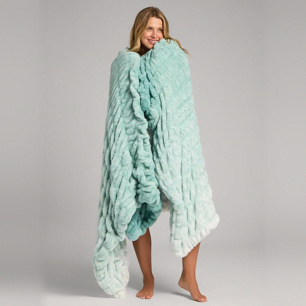 Mochi Mellow Cloud Throw in Mint Ombré — Mint ombré ruched faux-fur throw held around a woman's shoulders, fading to white at the hem