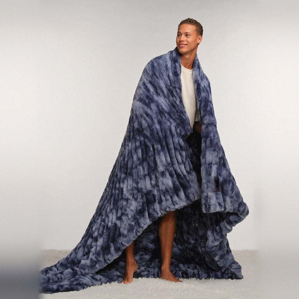 Mochi Mellow Cloud Throw in Navy Marble — Navy marble ruched faux-fur throw draped over a man's shoulders, pooling on the floor