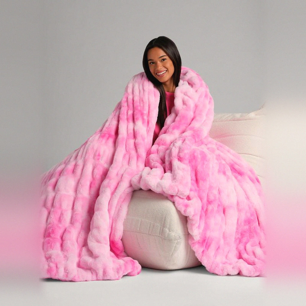 Mochi Mellow Cloud Throw in Pink Marble — Pink marble ruched faux-fur throw wrapped around a woman on a cream lounger