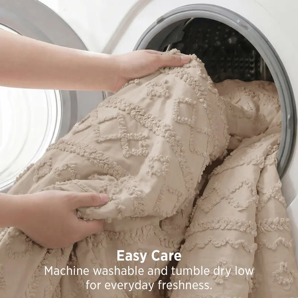 Tufted comforter going into a front-loading washing machine — machine washable, tumble dry low